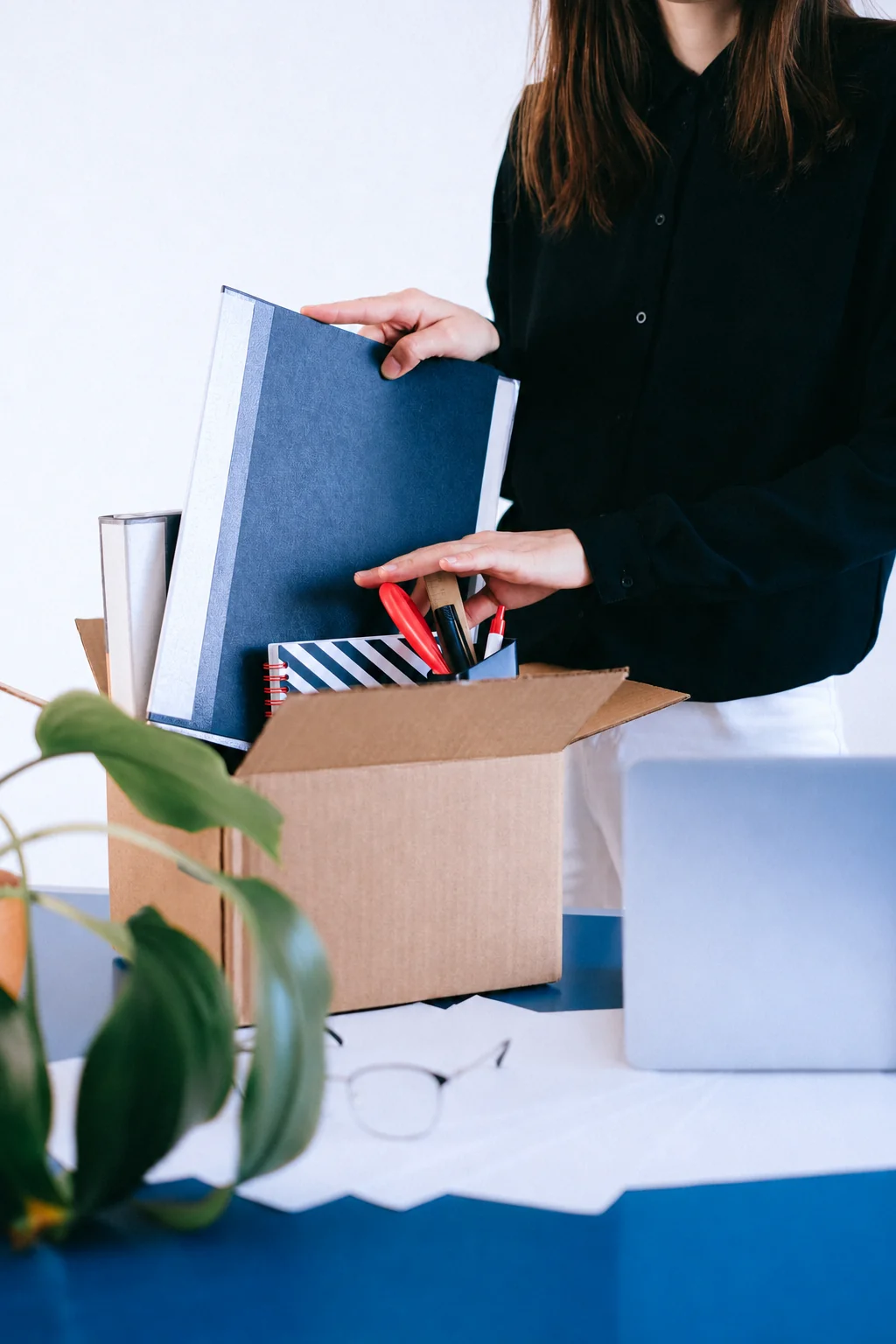 Packing documents and office belongings into a cardboard box.